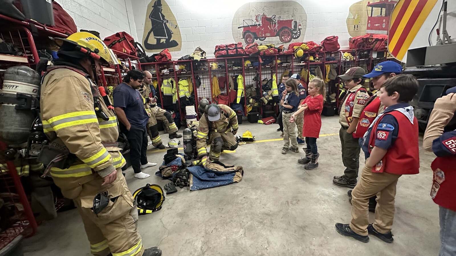 Cub Scouts watching firefighters lay out turnout gear at the fire station